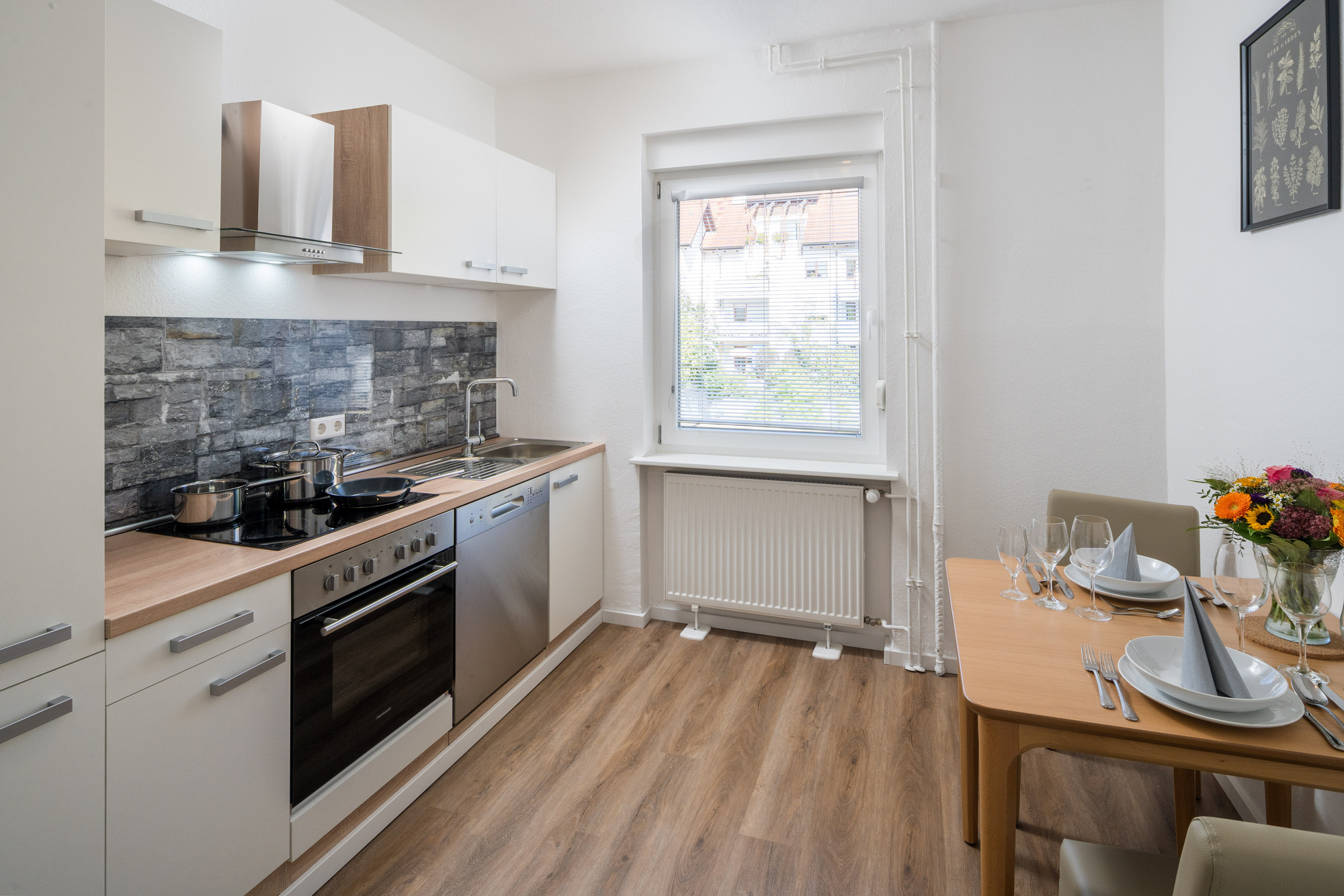 Moderne Longstay-Küche im Best Western Hotel Lamm mit weißen Schränken, Essbereich für zwei und natürlichem Licht durch Fenster.